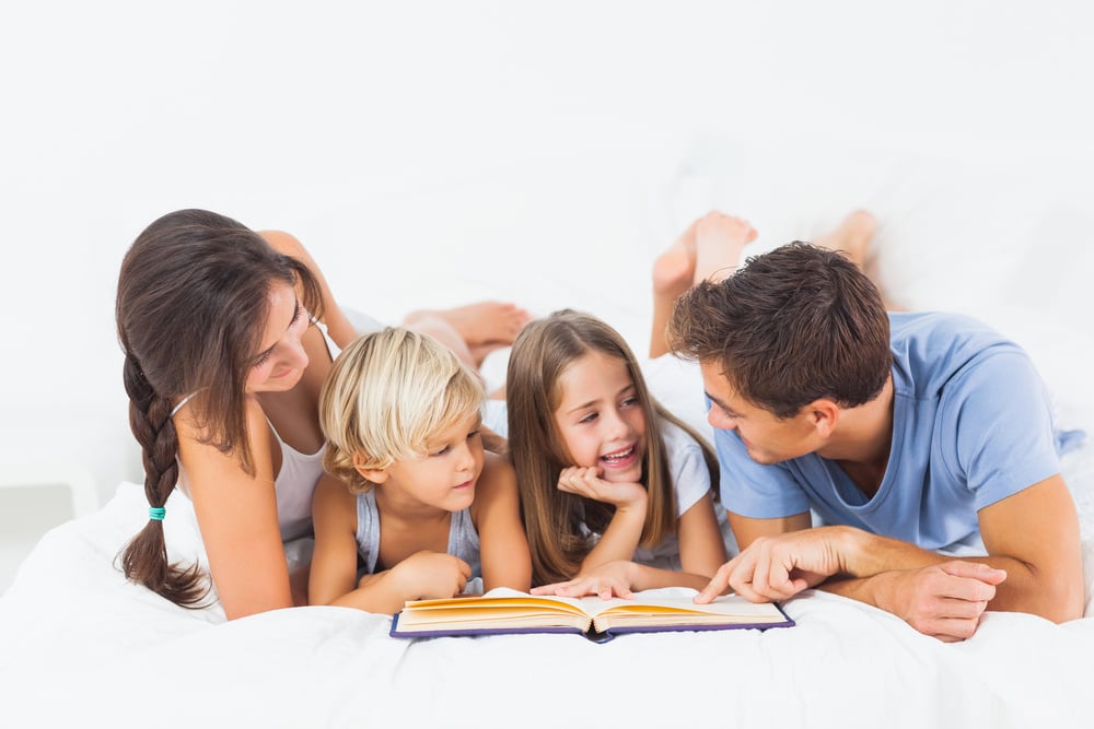 Family reading book on the bed in the bedroom